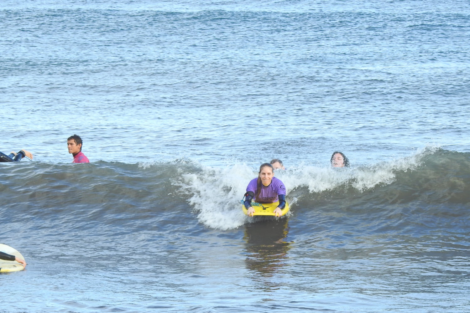 Female bodyboarder riding a wave with a happy face while doing her group bodyboard lesson in madeira