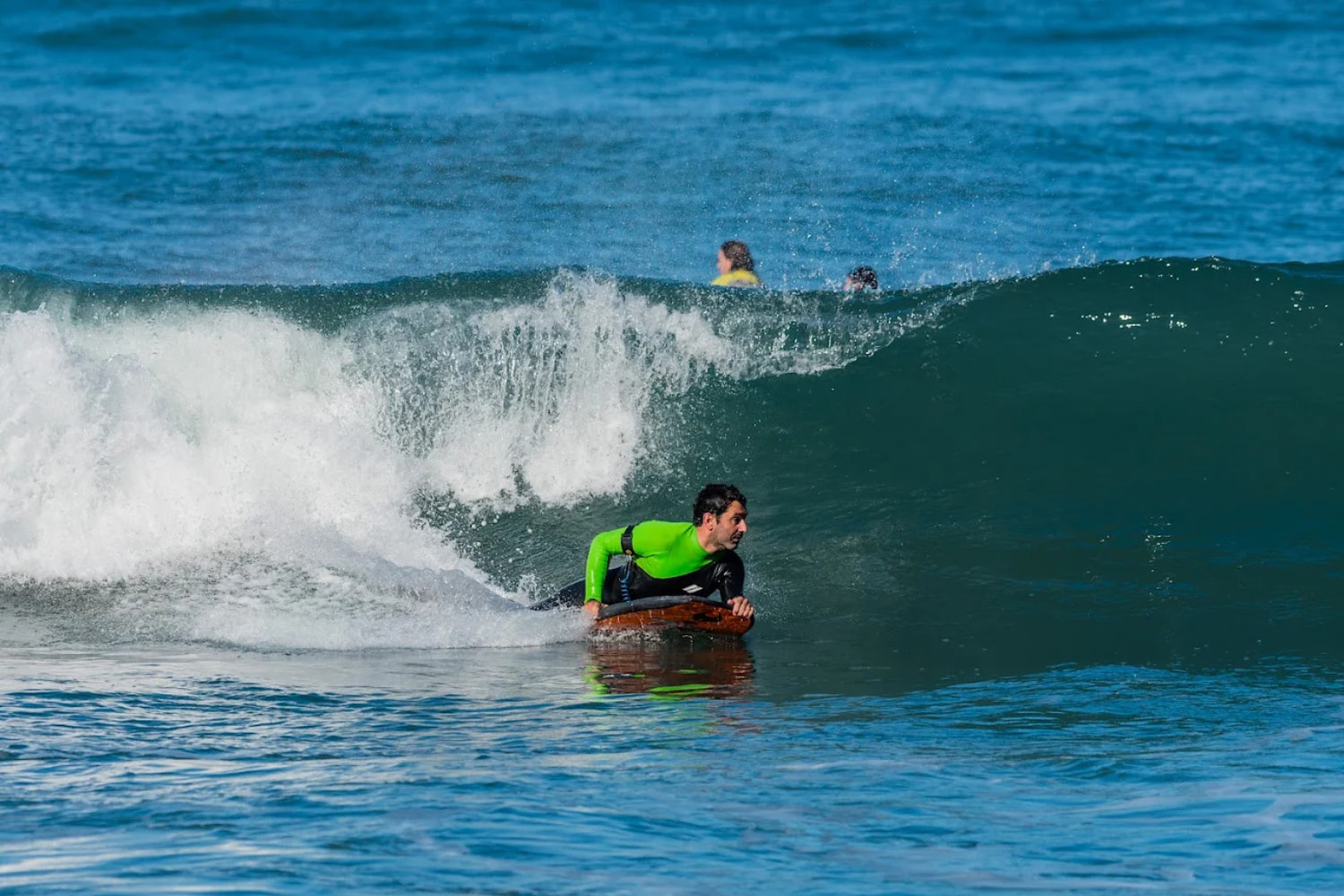 Bodyboarder riding a wave while in a group bodyboard lesson in seixal