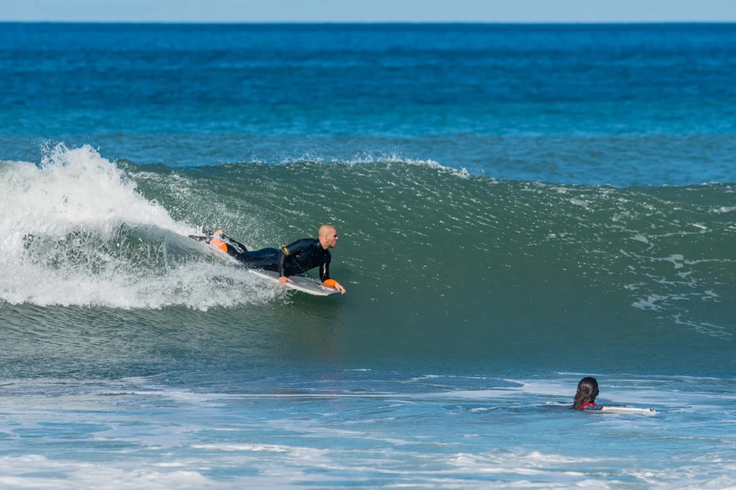 A professional male bodyboarder riding a big wave while doing his group bodyboard lesson in madeira