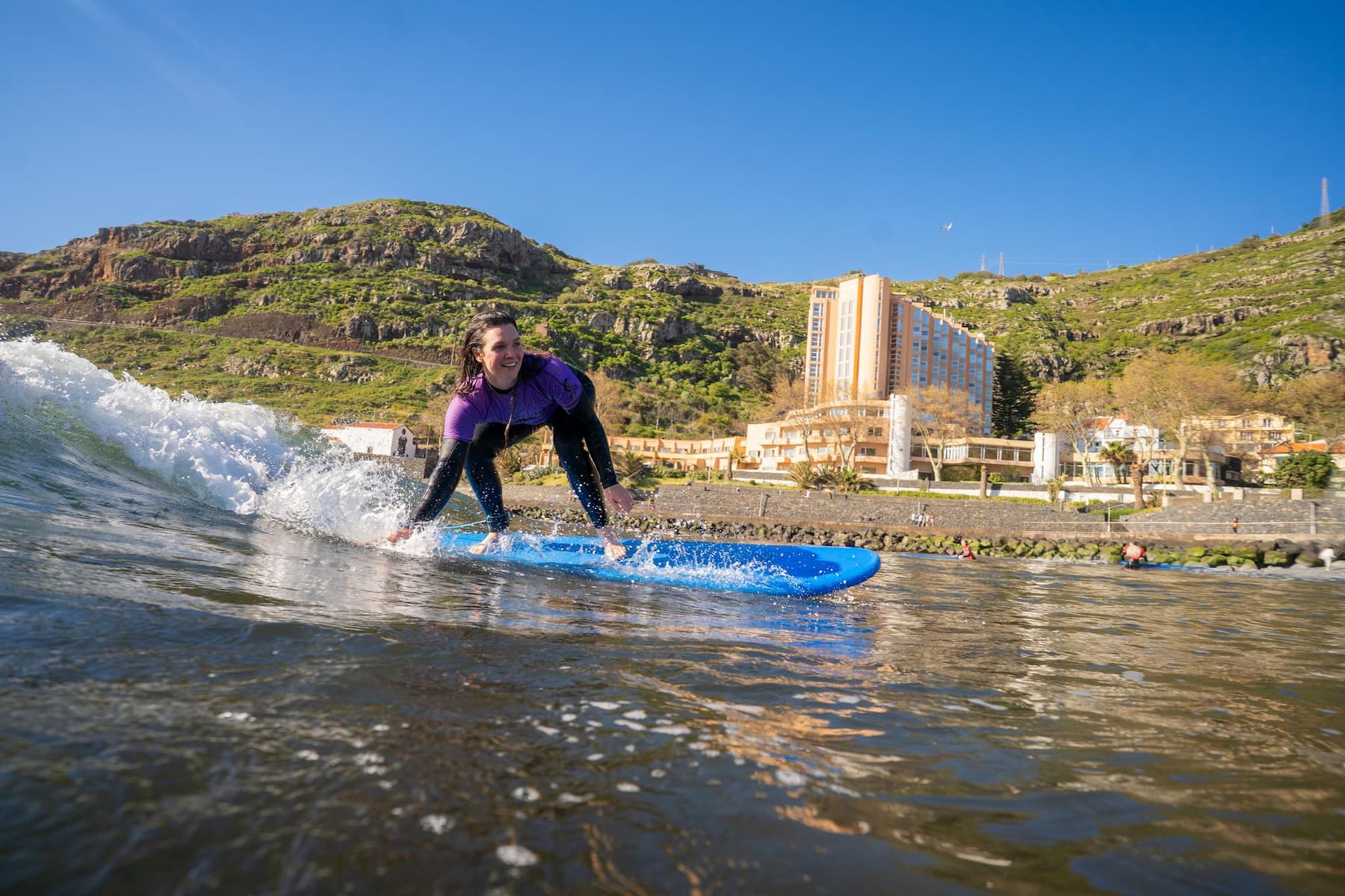 Female surfer riding a wave in Machico's beach while doing a surf lesson in Machico