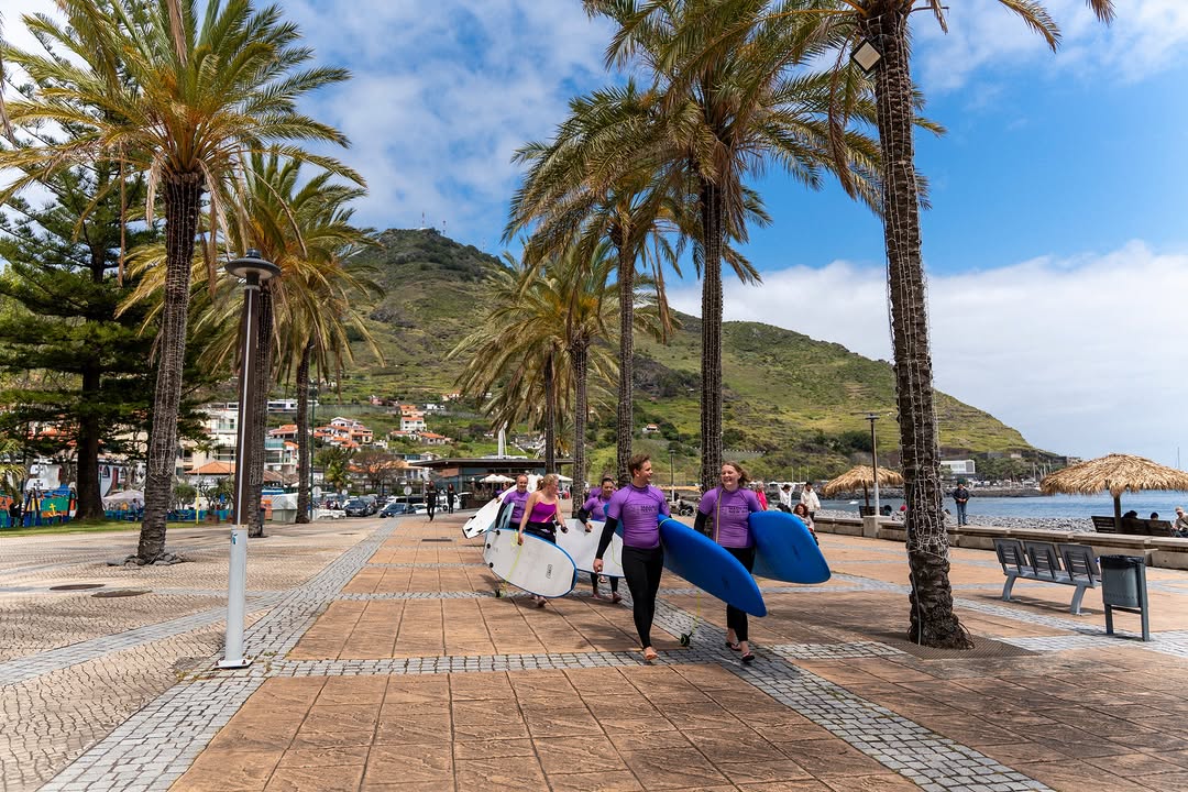 A group of surfers walking in front of Machico's beach, preparing to do a group surf lesson in Machico