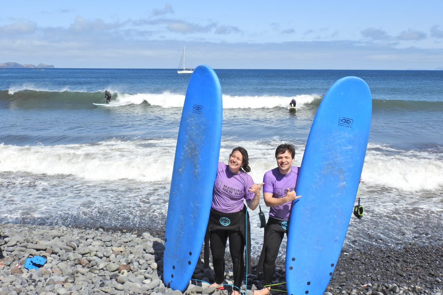 A happy couple of surfers with their surf boards before starting their private surf lesson for couples in madeira