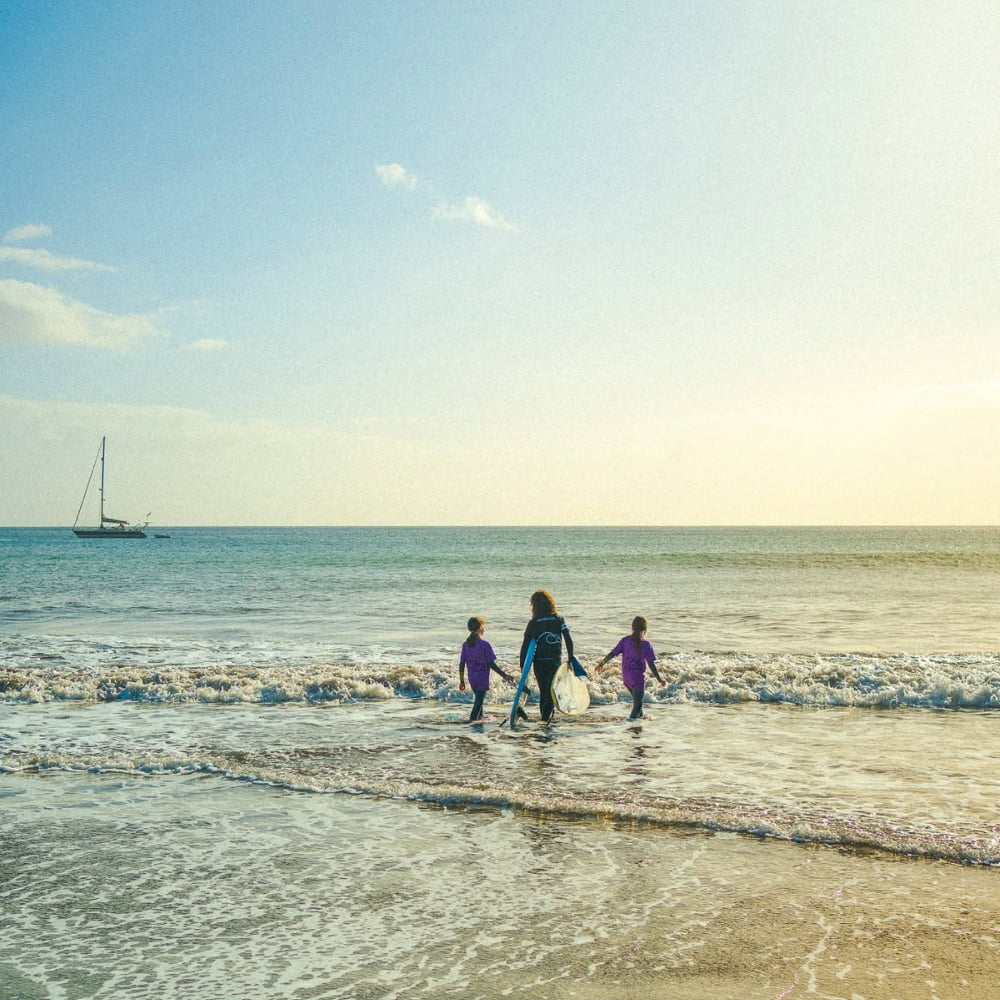 Young kids with a surf instructor while doing a kids surf lesson in madeira