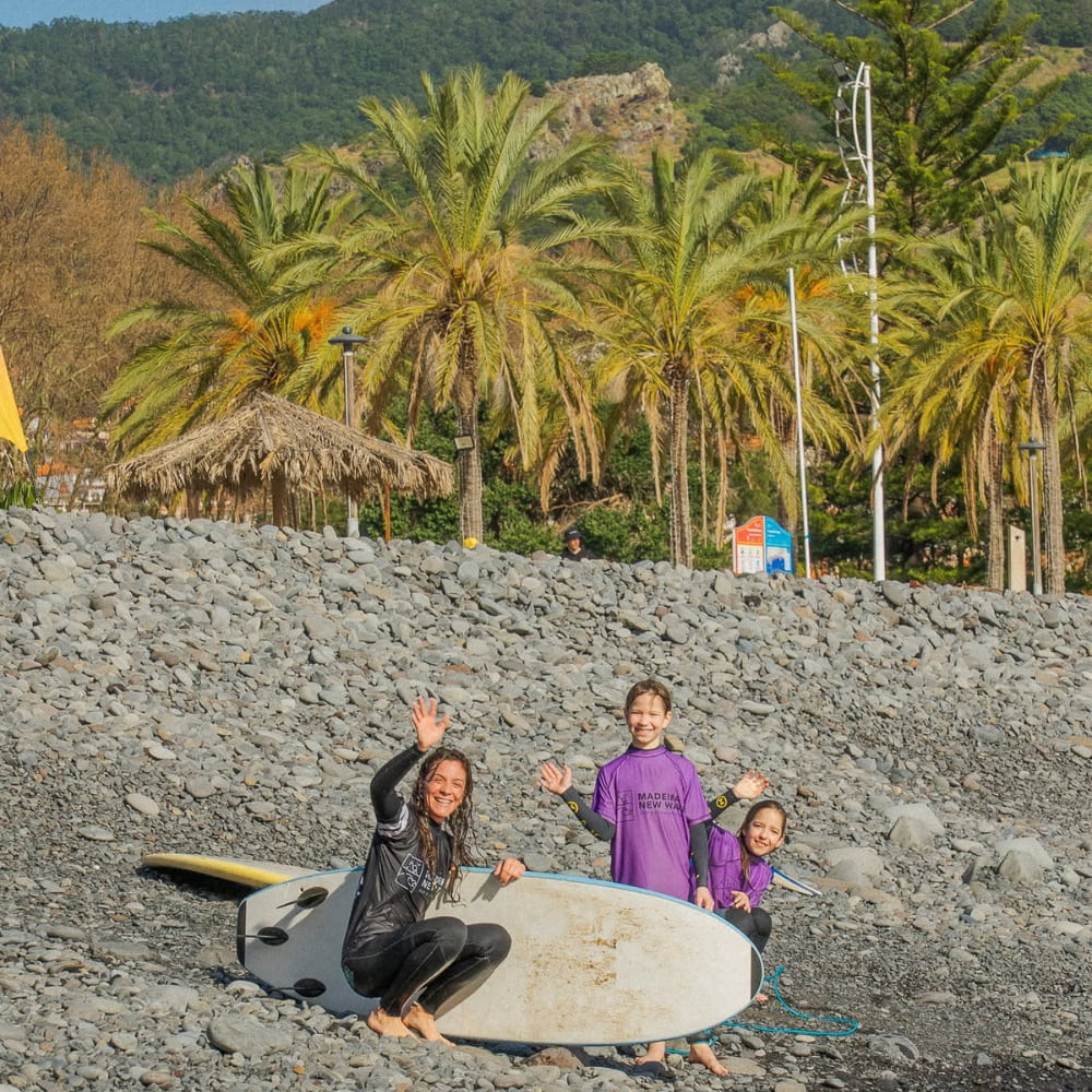 Two young surfer kids happy while doing a surf lesson for kids in madeira